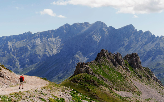 Hiker on Mirador del Cable to Espinama Trail with Picos de Europa mountains, Fuente De, Spain.