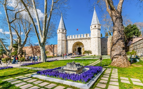 Gate of Salutation at Topkapi Palace, Istanbul, with gardens and visitors.