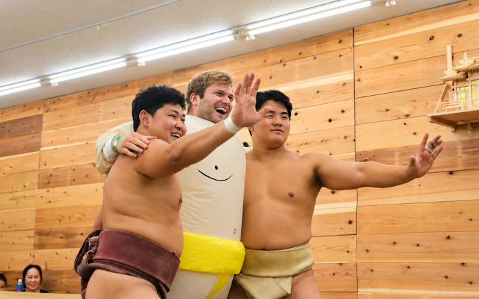 Tourist with two sumo wrestlers at Osaka Live Sumo Show.