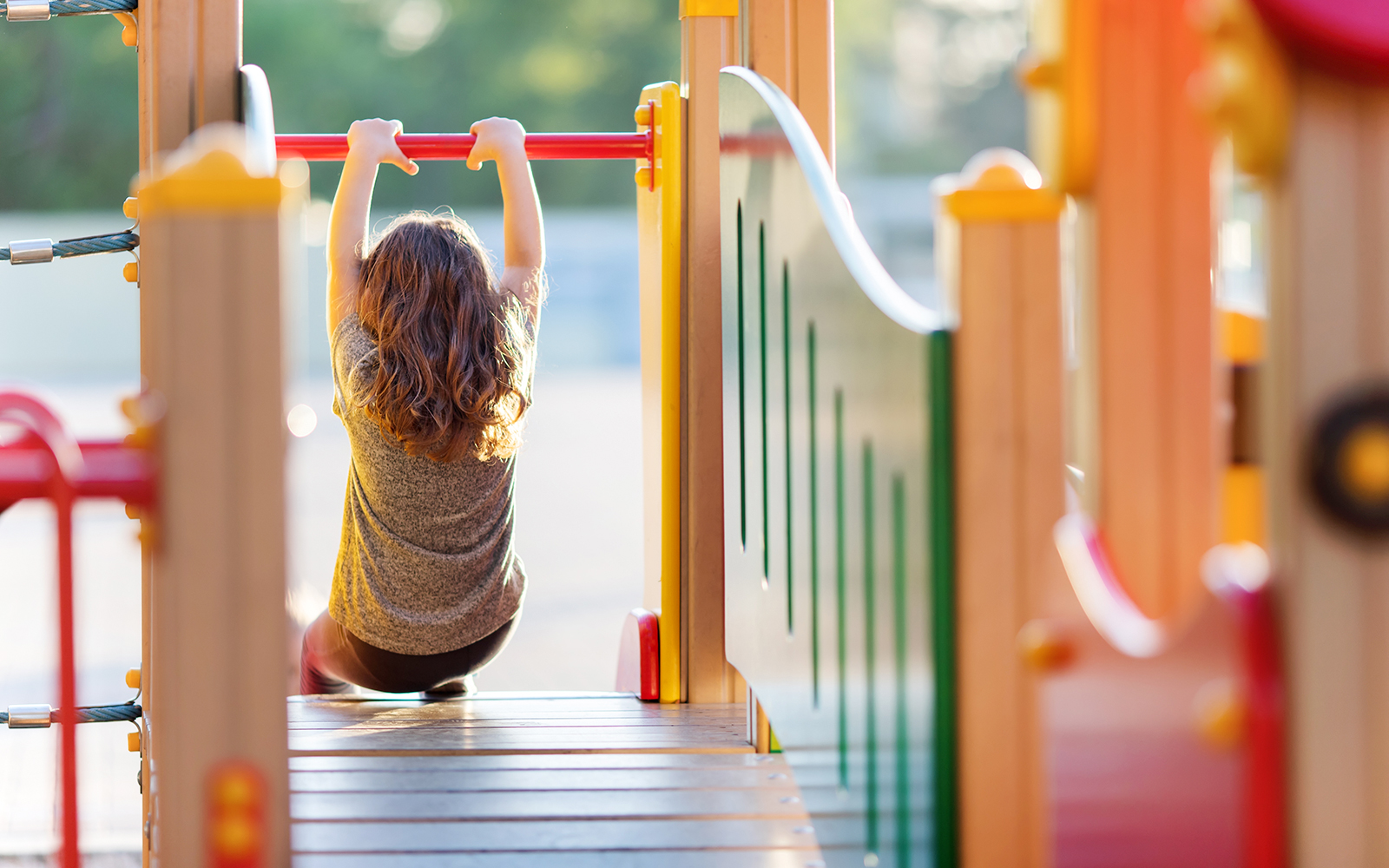 Child playing on monkey bars at a colorful playground.