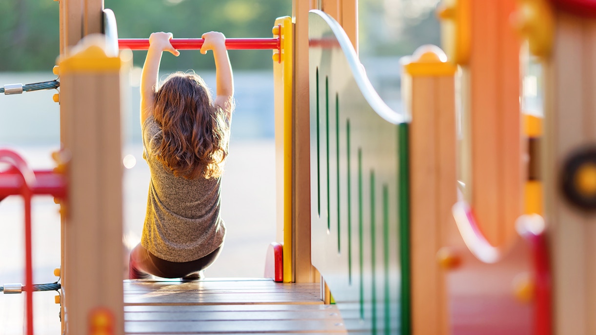 Child playing on monkey bars at a colorful playground.
