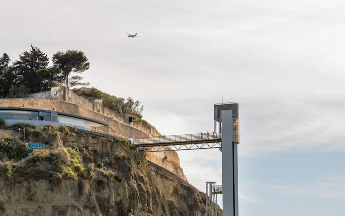Cliffside view with a modern elevator and walkway near Ribeira do Cavalo Beach, Lisbon.