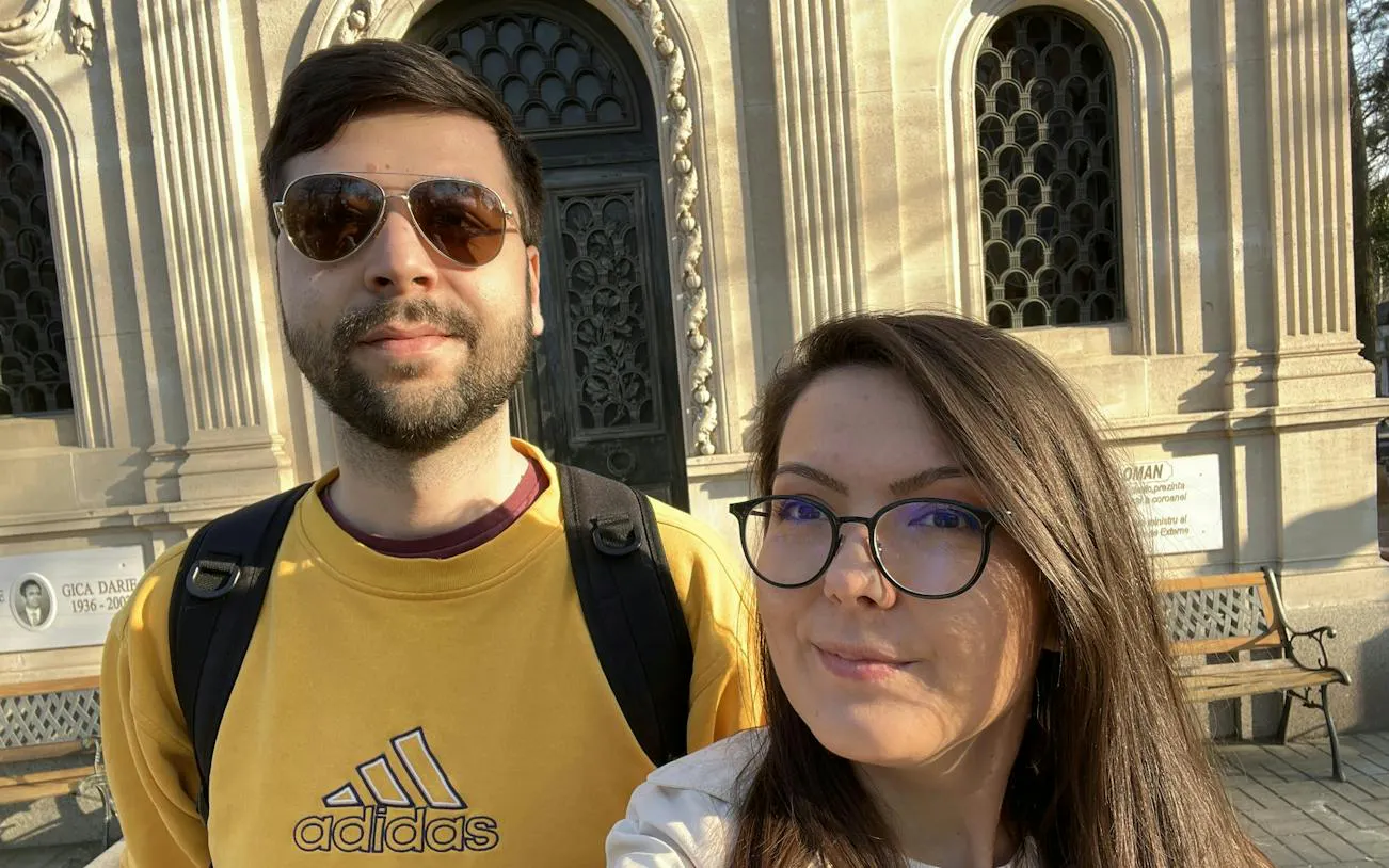 Two people in front of a historic mausoleum at Bellu Cemetery, Bucharest.