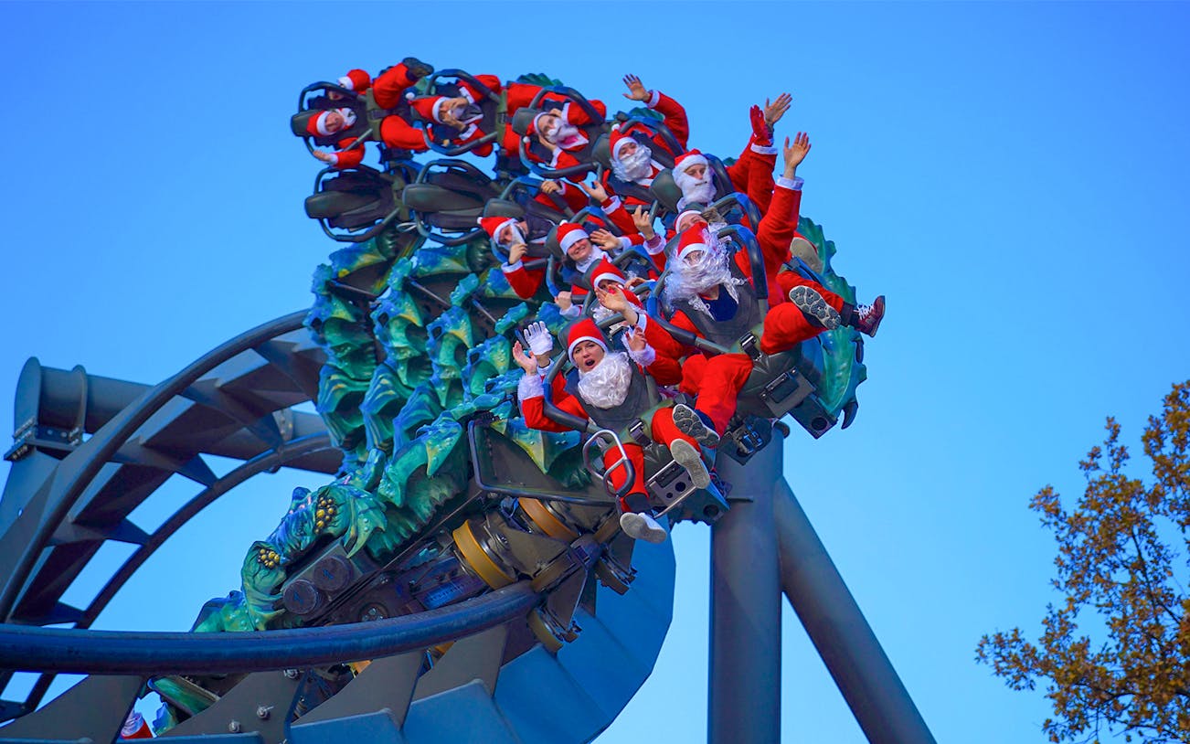 Visitors in Santa costumes on a roller coaster at Gardaland Park.