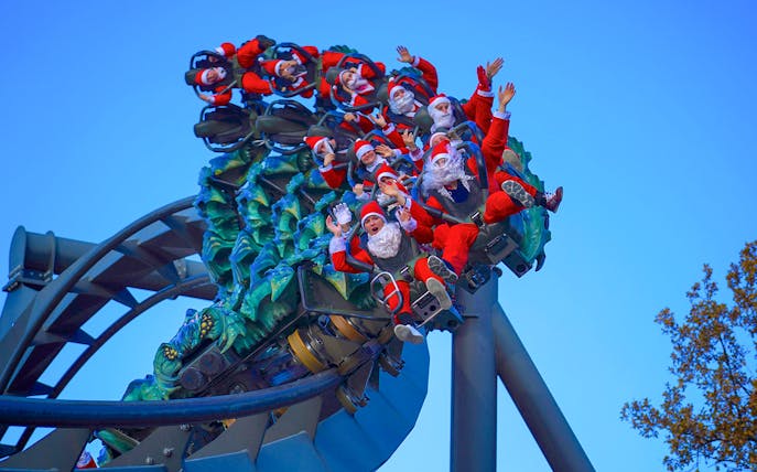 Visitors in Santa costumes on a roller coaster at Gardaland Park.