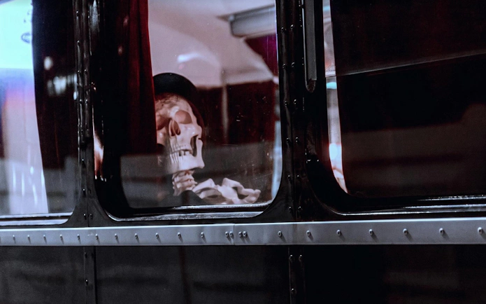 Skeleton in a hat inside a ghost bus tour vehicle.