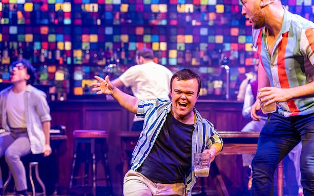 Performers energetically singing and holding drinks on stage during The Choir of Man show.