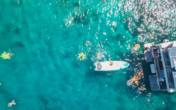 People swimming near a boat in clear blue waters during Split: Hvar & 3 islands cruise.