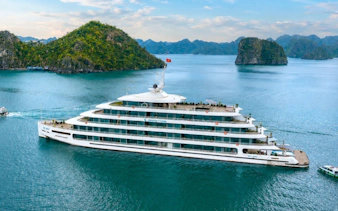 Luxury cruise ship sailing in Ha Long Bay with limestone islands in the background.