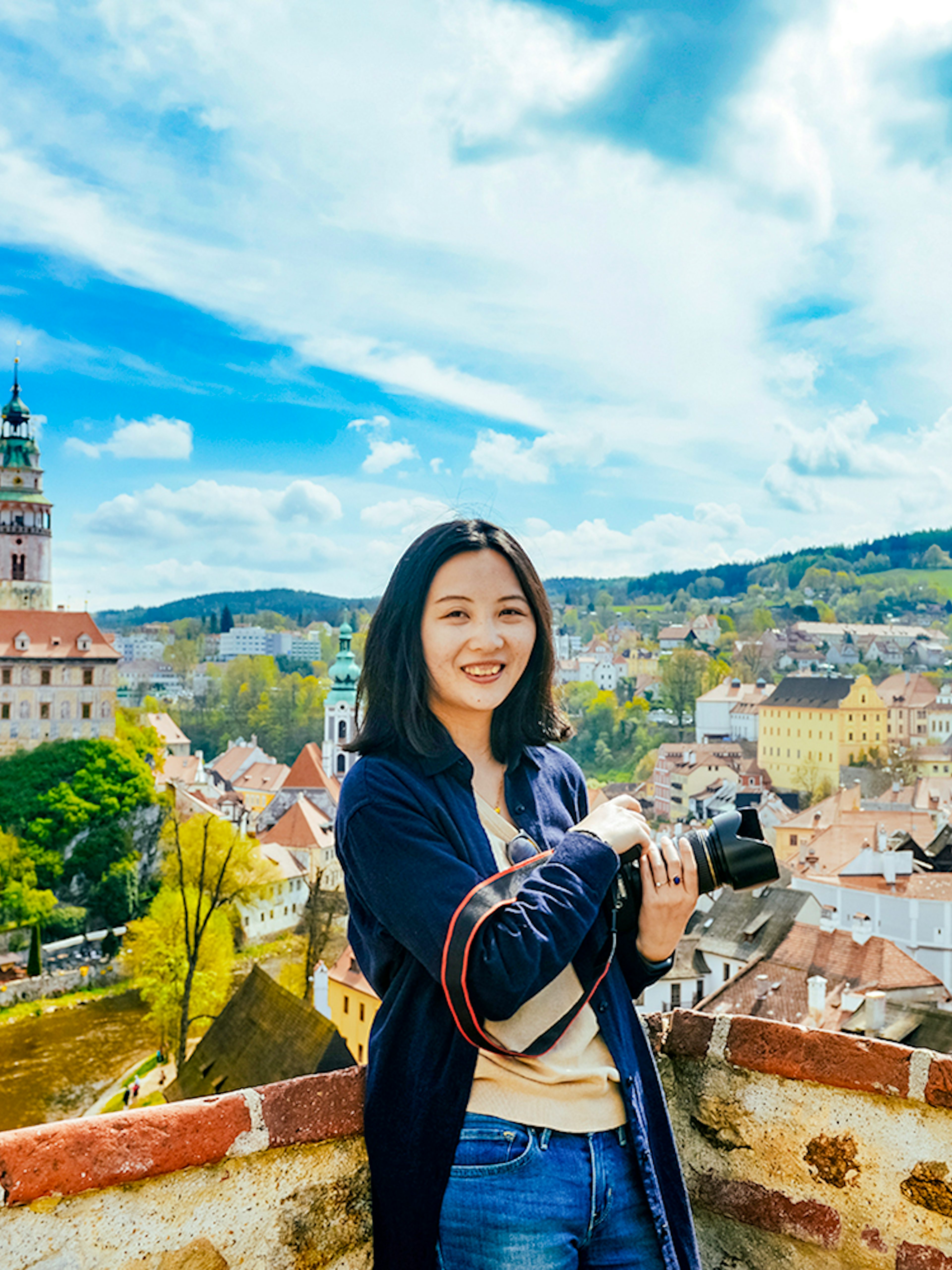 Tourist with camera overlooking Cesky Krumlov's colorful medieval buildings, Czech Republic.