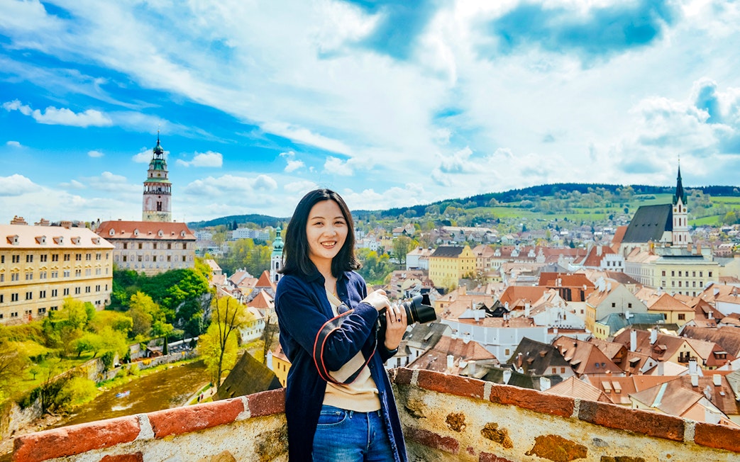 Tourist with camera overlooking Cesky Krumlov's colorful medieval buildings, Czech Republic.