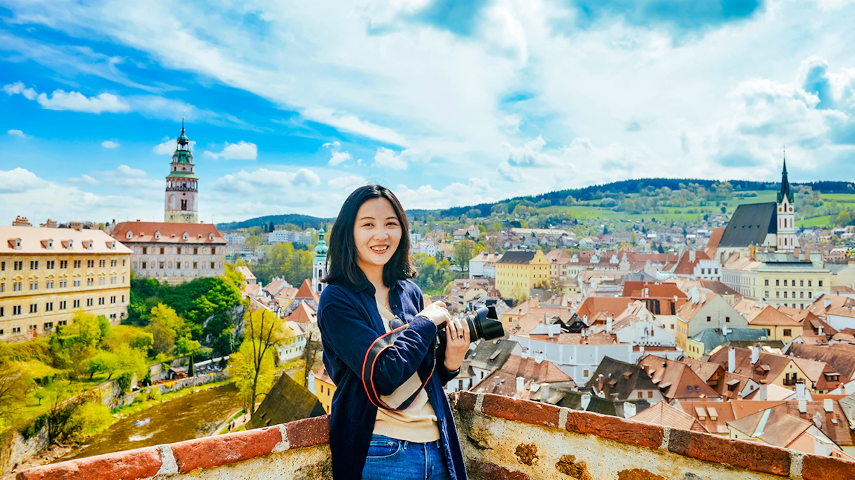 Tourist with camera overlooking Cesky Krumlov's colorful medieval buildings, Czech Republic.