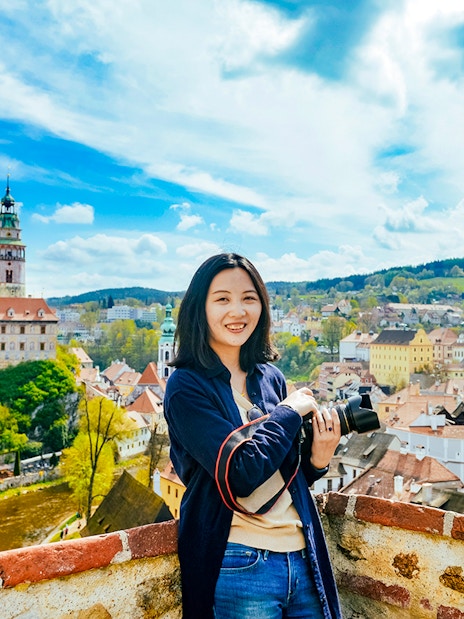 Tourist with camera overlooking Cesky Krumlov's colorful medieval buildings, Czech Republic.