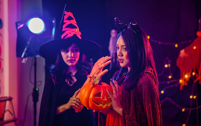 Two people in Halloween costumes holding a carved pumpkin during Bran Dracula's Castle tour.