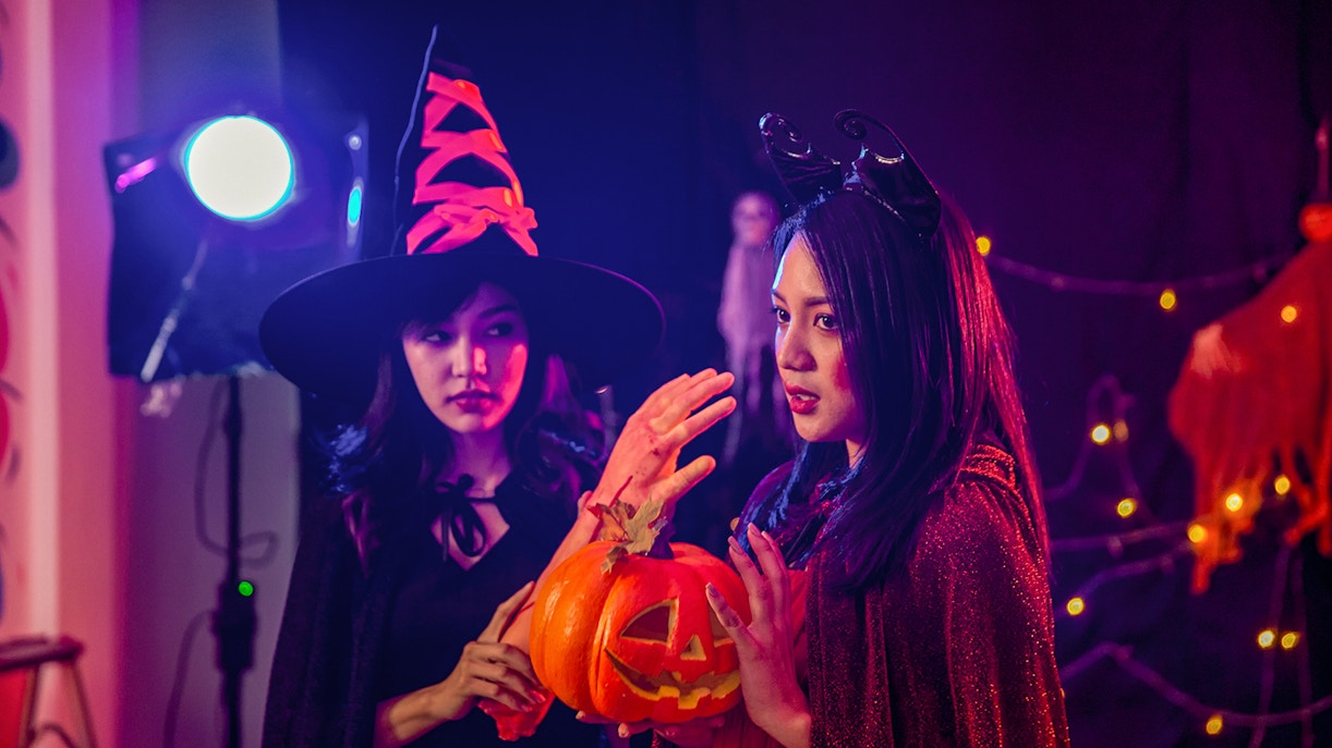 Two people in Halloween costumes holding a carved pumpkin during Bran Dracula's Castle tour.
