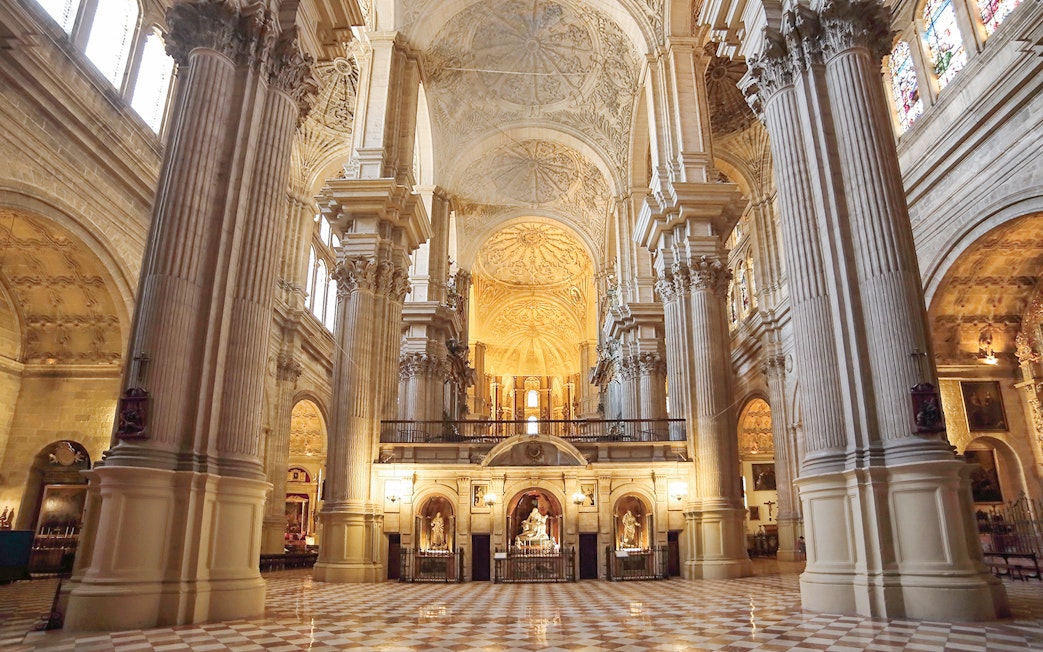 Interior of the Cathedral of Málaga with ornate columns and vaulted ceilings.