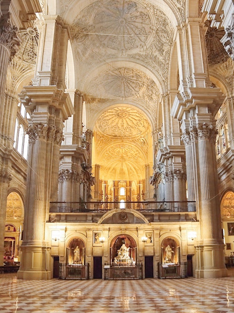 Interior of the Cathedral of Málaga with ornate columns and vaulted ceilings.