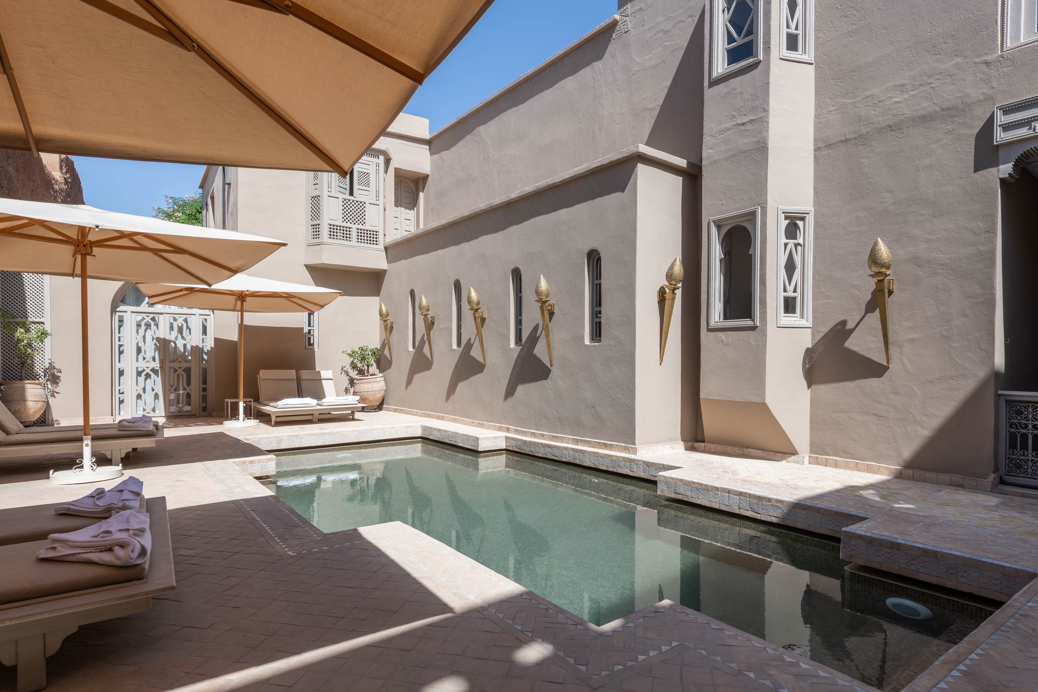 Courtyard pool with sun loungers and umbrellas at a luxury steam hammam and spa.