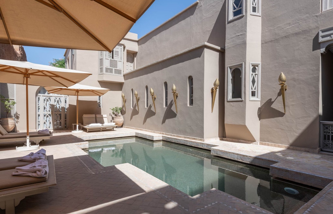 Courtyard pool with sun loungers and umbrellas at a luxury steam hammam and spa.