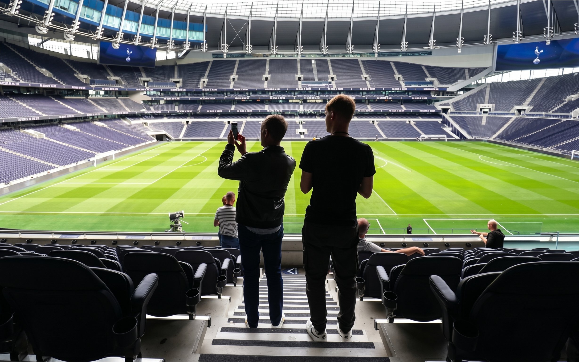 Visitors taking photos inside Tottenham Hotspur Stadium during a tour.