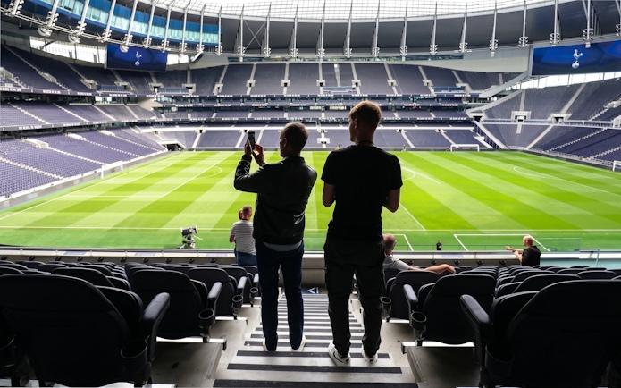 Visitors taking photos inside Tottenham Hotspur Stadium during a tour.