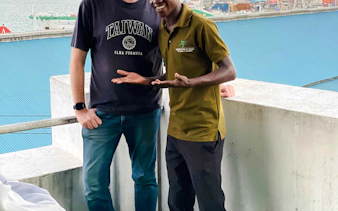 Tour guide with visitor on a balcony overlooking Zanzibar harbor.