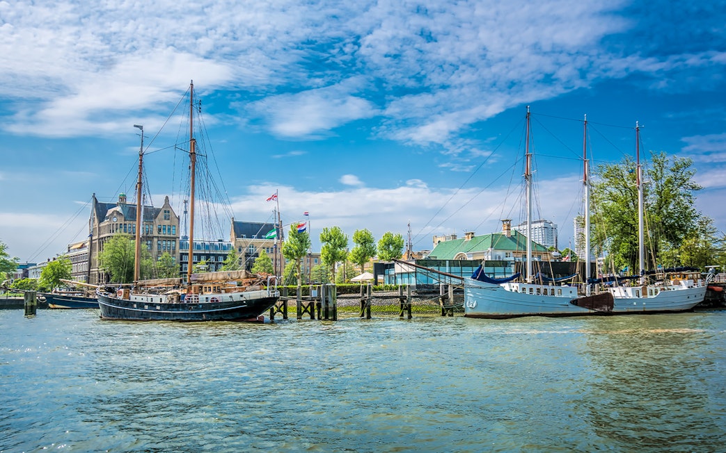 Sailboats docked at Veerhaven harbor in Rotterdam, Netherlands, with historic buildings in the background.