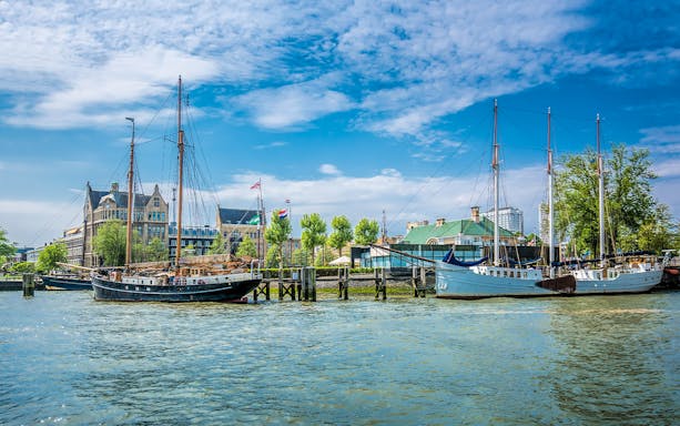 Sailboats docked at Veerhaven harbor in Rotterdam, Netherlands, with historic buildings in the background.