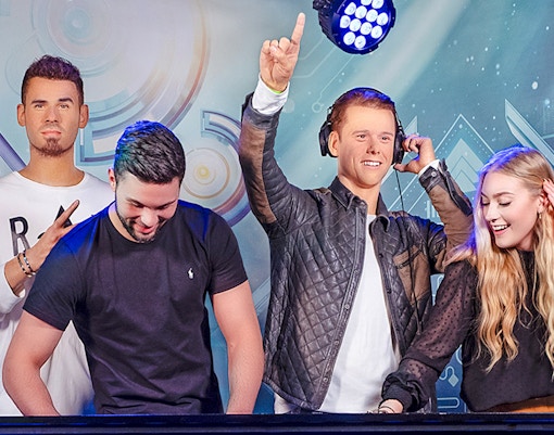 DJ figures at Madame Tussauds Amsterdam with visitors enjoying music.