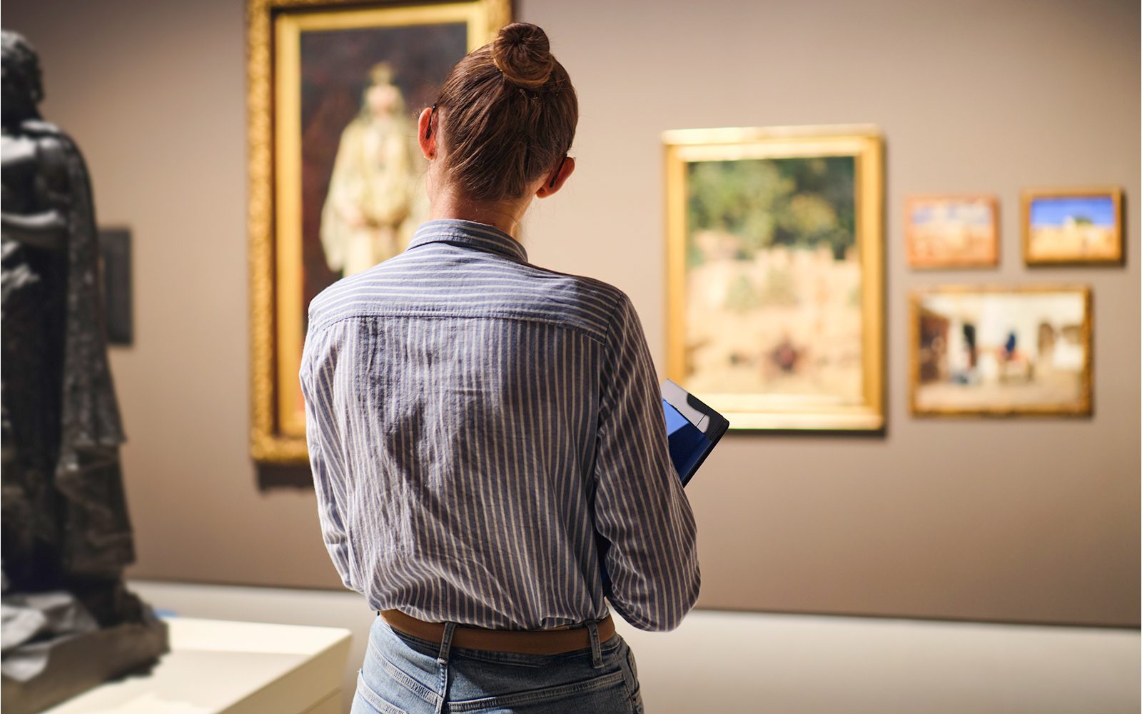 Backshot of a woman standing in front of a painting in the musuem