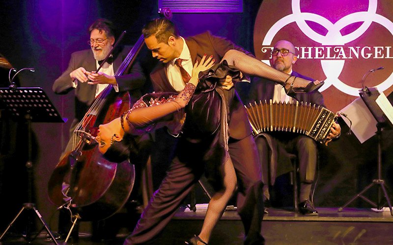 Dancers performing a dramatic tango at Michelangelo Tango Show with live musicians.