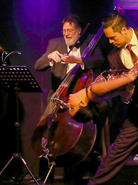 Dancers performing a dramatic tango at Michelangelo Tango Show with live musicians.
