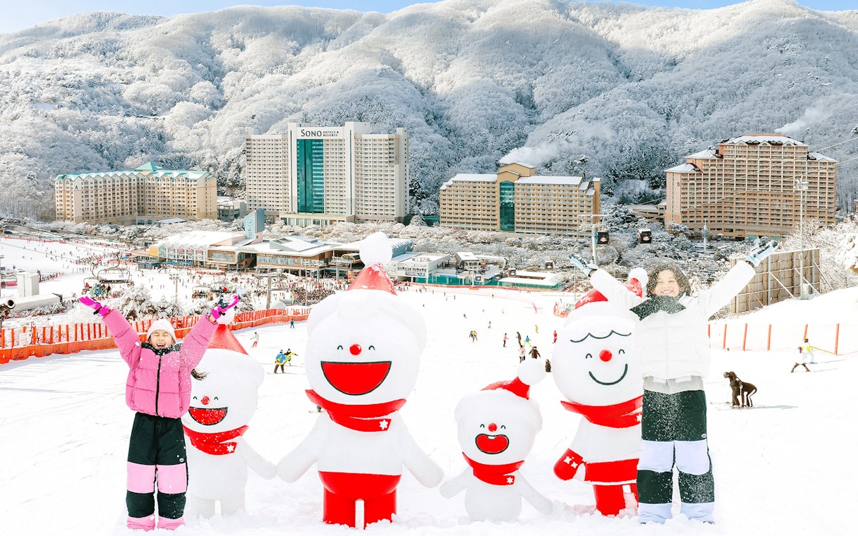 Family enjoying snow with snowman figures at Vivaldi Park Ski Resort, South Korea.