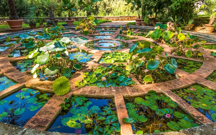 Upper Botanical Garden at Boboli Gardens with manicured hedges and statues in Florence, Italy.