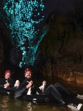 People black water rafting under glowworms in a cave.