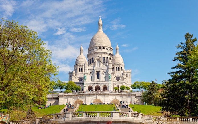 Basilica of the Sacred Heart in Paris with visitors on the steps.