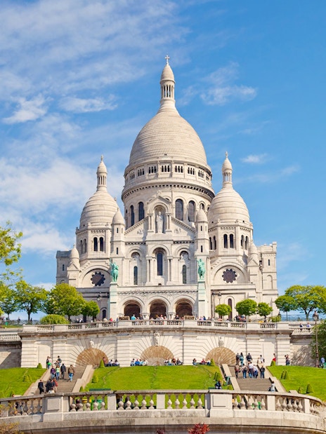 Basilica of the Sacred Heart in Paris with visitors on the steps.