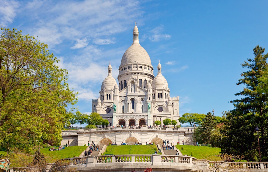Basilica of the Sacred Heart in Paris with visitors on the steps.