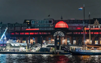 Grand Harbor evening cruise with illuminated waterfront building and docked ship.