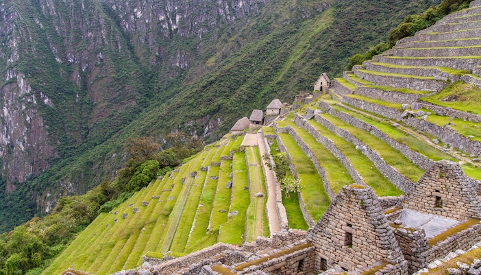 Terraced agriculture fields at Machu Picchu with stone structures and mountain backdrop.
