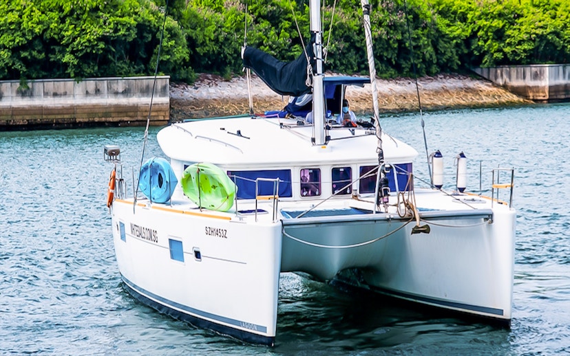 Private yacht SunRise sailing near lush shoreline with kayaks onboard.