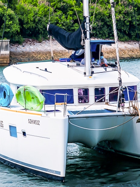Private yacht SunRise sailing near lush shoreline with kayaks onboard.
