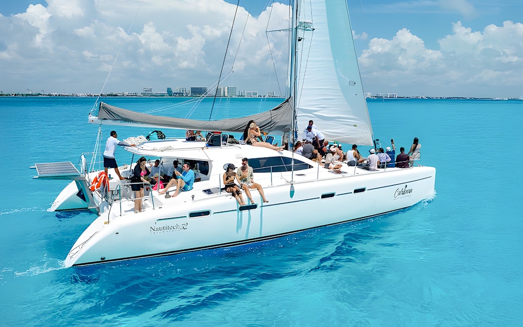 Catamaran cruise with passengers on turquoise Caribbean Sea near Cancún, Mexico.