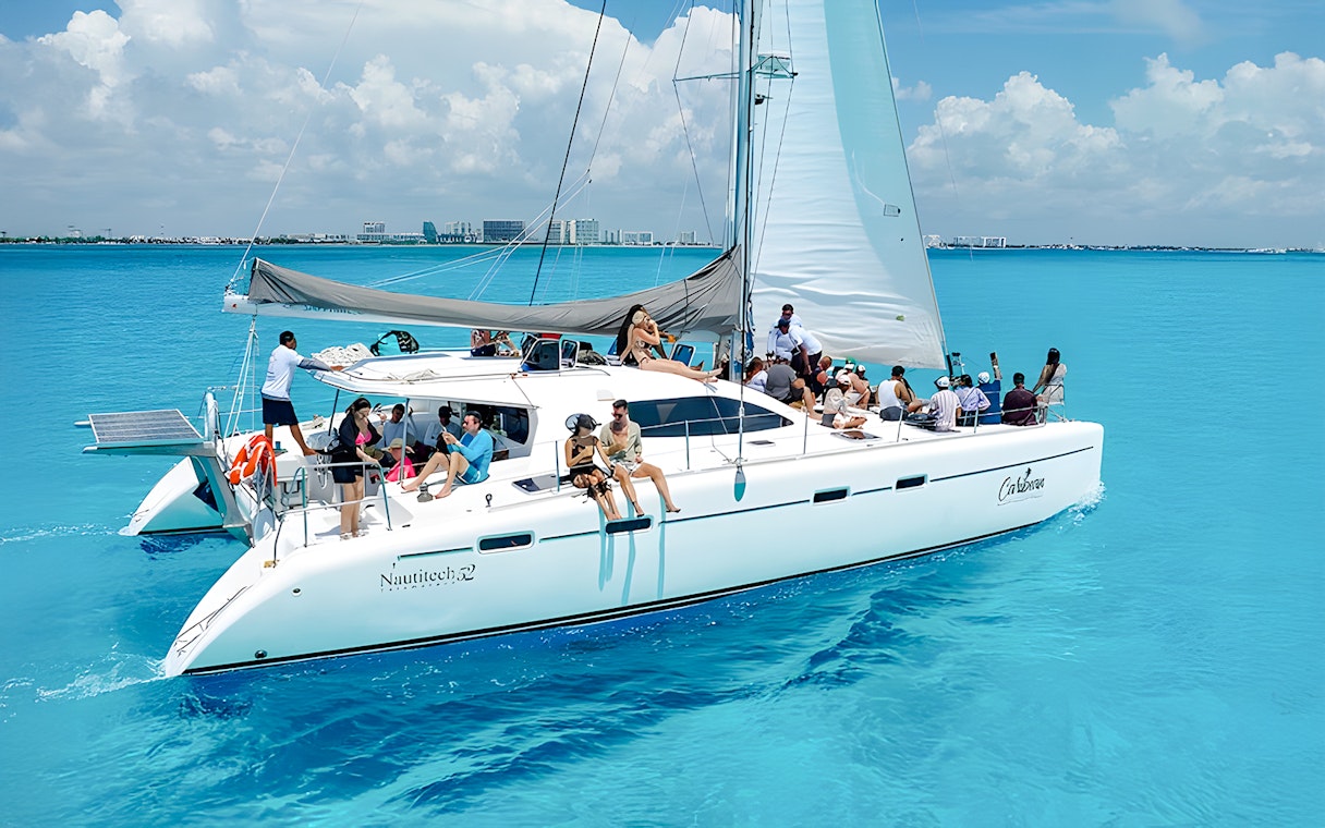 Catamaran cruise with passengers on turquoise Caribbean Sea near Cancún, Mexico.