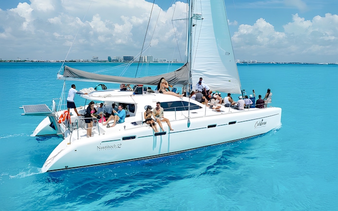 Catamaran cruise with passengers on turquoise Caribbean Sea near Cancún, Mexico.