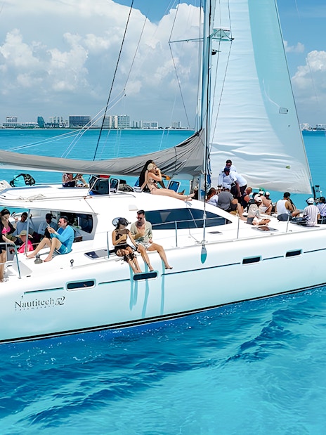 Catamaran cruise with passengers on turquoise Caribbean Sea near Cancún, Mexico.