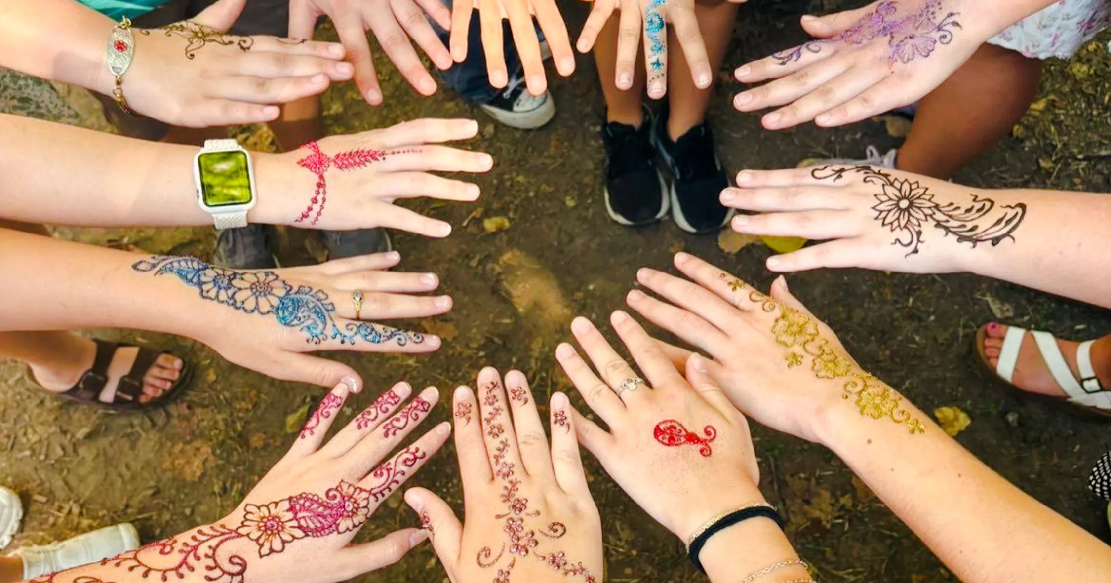 Hands displaying colorful henna designs at Essaouira Craft Complex workshop.