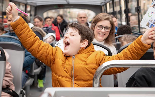Joyful child celebrating quiz win on Tootbus tour in Paris.