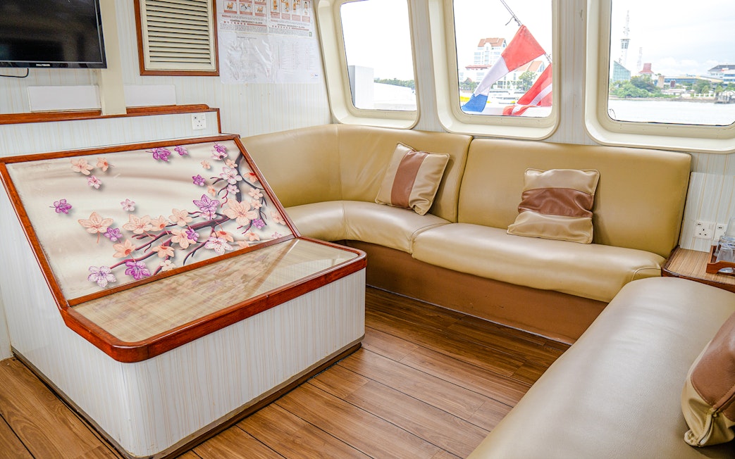 Ferry interior with beige seating and floral artwork, Singapore to Batam route.