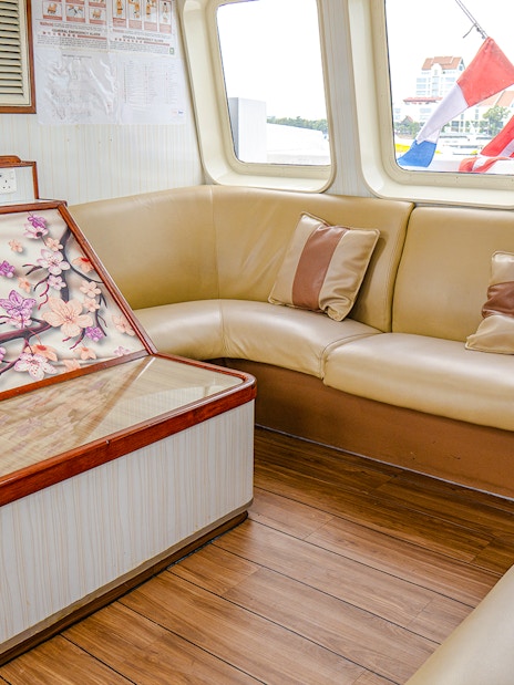 Ferry interior with beige seating and floral artwork, Singapore to Batam route.